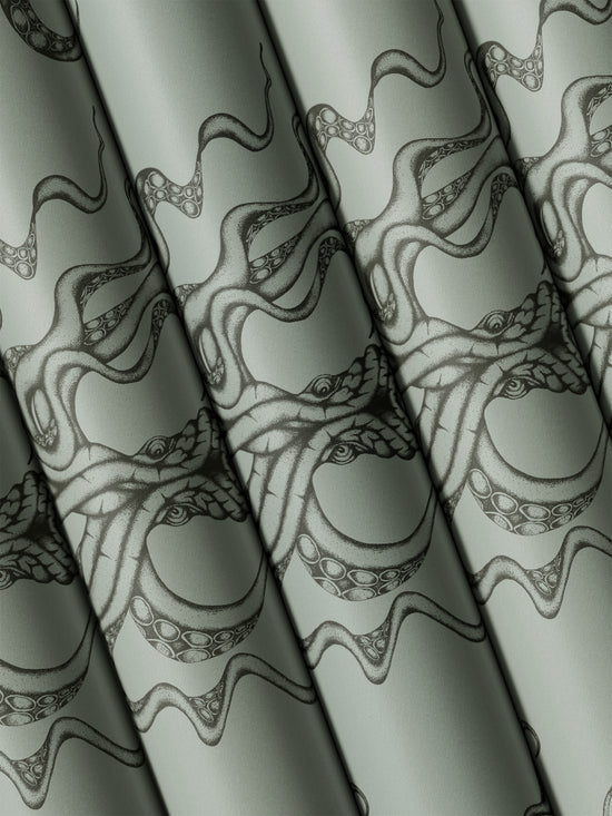 Multiple rolls of Kraken Steel wallpaper folded to reveal moody sea monster print in shimmering tones.