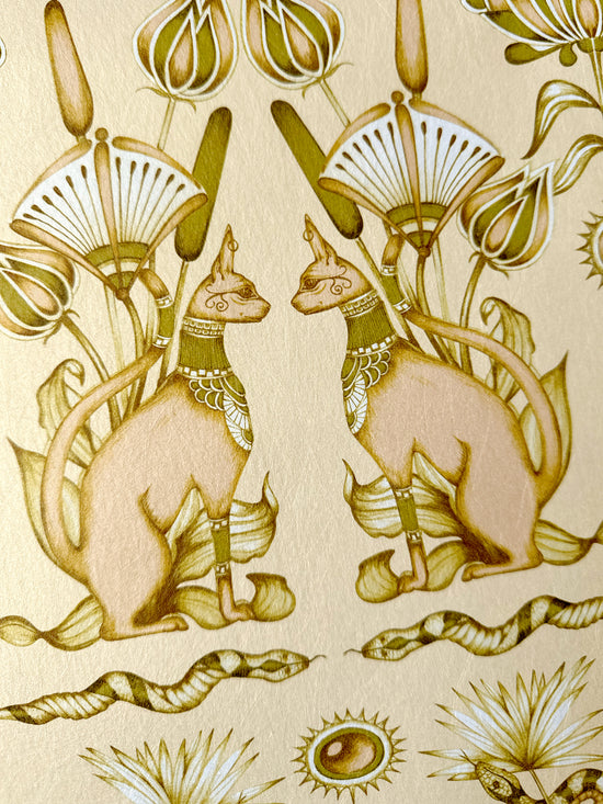 Nefertiti Cream wallpaper featuring cats and snakes on a soft peach and gold background.