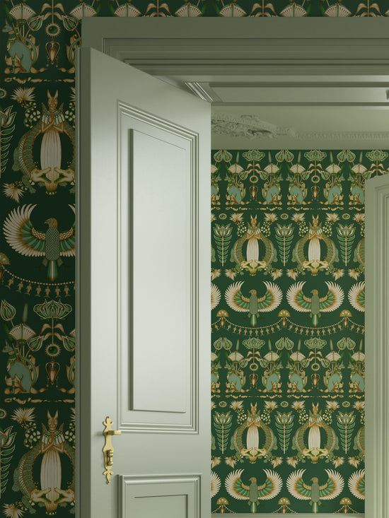 Bedroom setting with Nefertiti Green wallpaper featuring Egyptian floral motifs and gold tones.