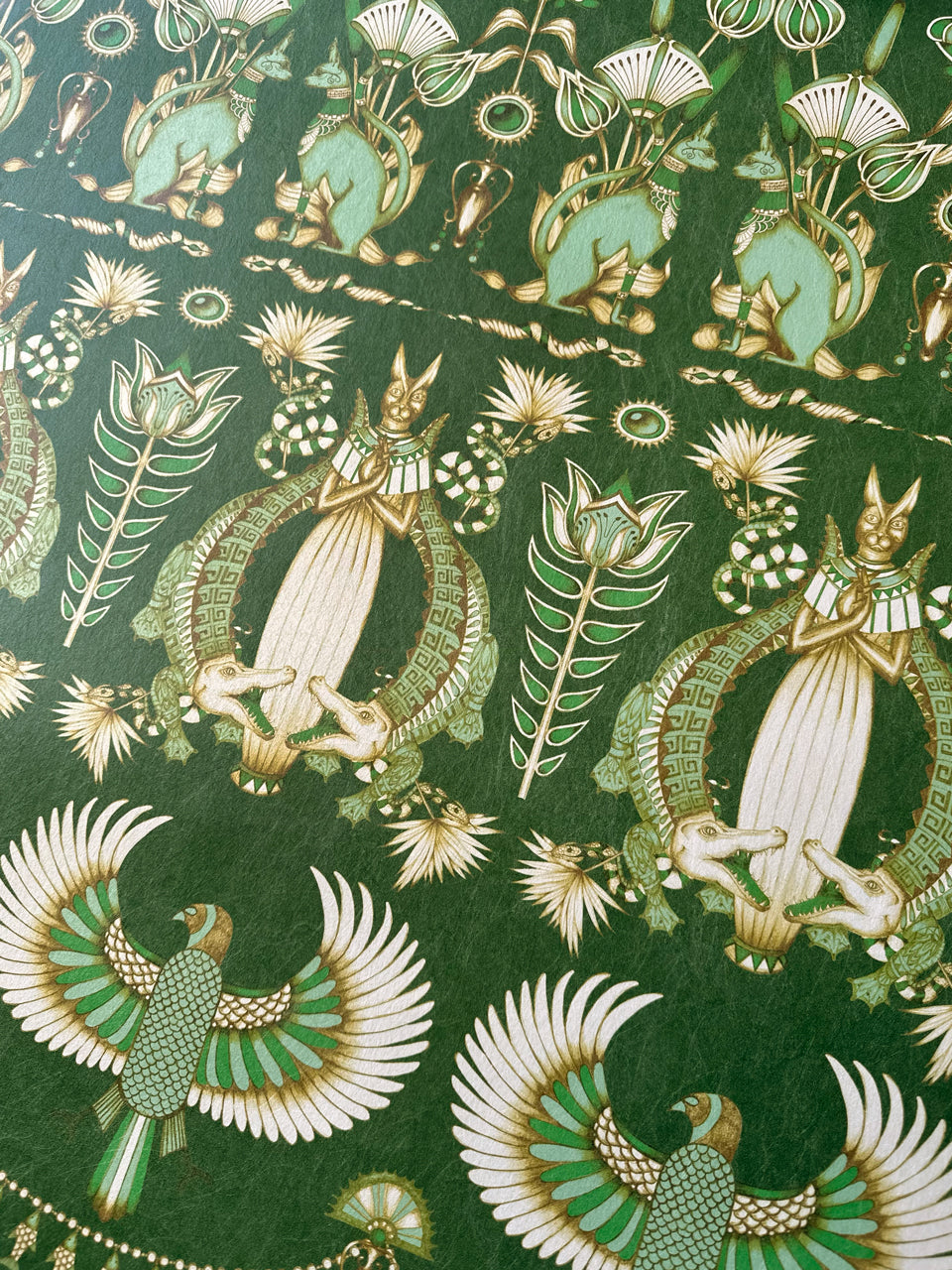 Opulent close-up of emerald palms on deep green Nefertiti Green wallpaper with fine gold print.