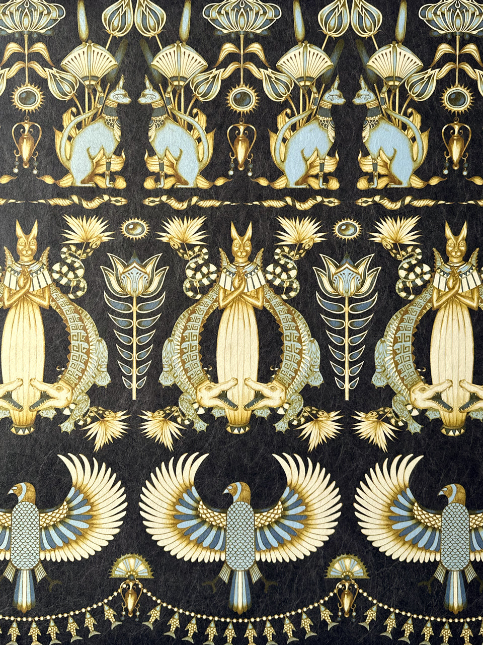Close-up of Nefertiti Navy wallpaper featuring sacred cats, crocodiles, and Egyptian motifs in dark navy and gold.