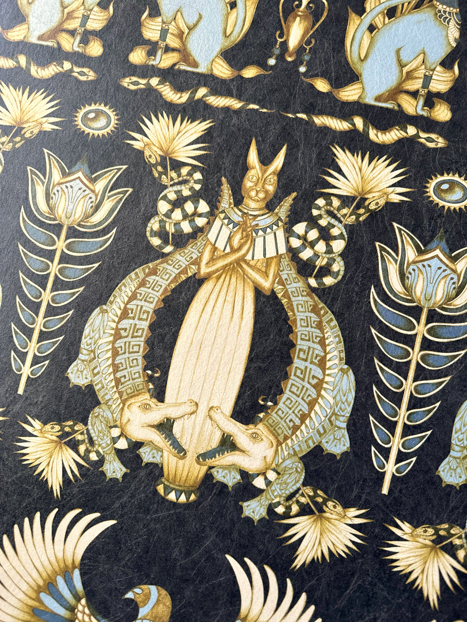 Detailed view of crocodile and sacred cat in Nefertiti Navy wallpaper on midnight blue and gold parchment.