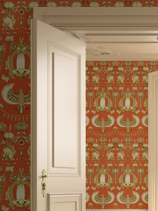 Nefertiti Orange wallpaper in a warm, bohemian bedroom with bold ancient Egyptian illustrations.