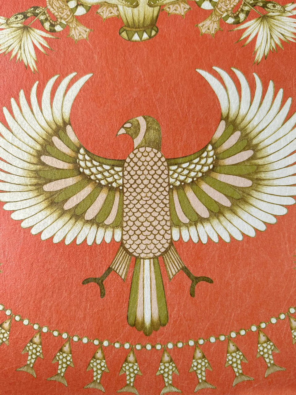 Hand-drawn bird with extended wings and golden fish detailing on rich orange wallpaper.