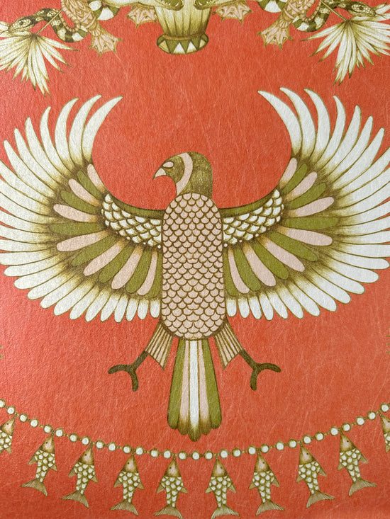 Hand-drawn bird with extended wings and golden fish detailing on rich orange wallpaper.