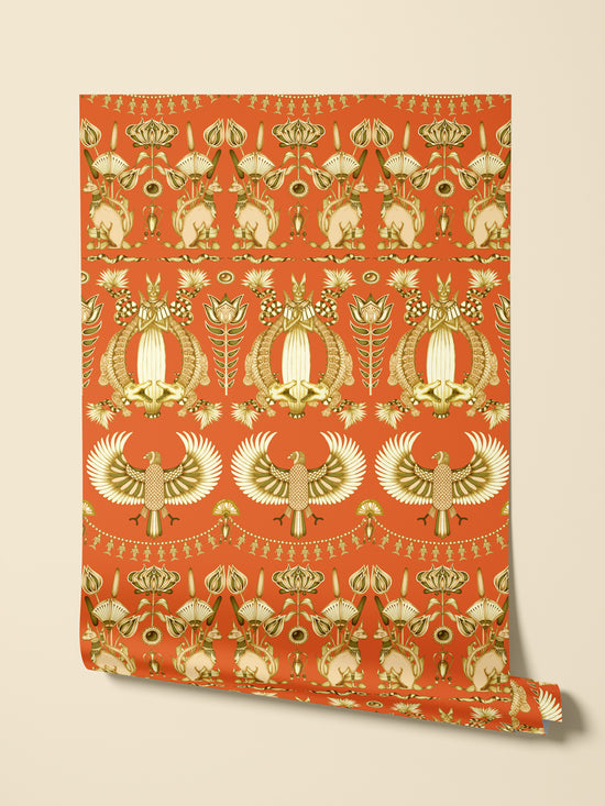 Hanging roll of Nefertiti Orange wallpaper showing full repeat in gold parchment-style paper.