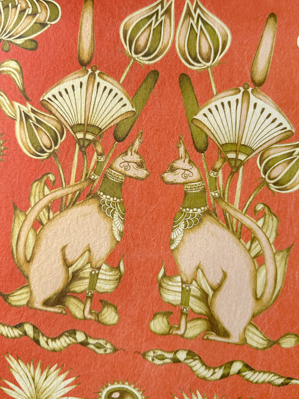 Paired Egyptian cats seated among floral motifs in nude peach and olive on burnt orange background.