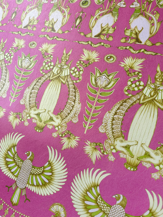 Raspberry-toned close-up of floral Egyptian motifs on shimmering art deco wallpaper design.
