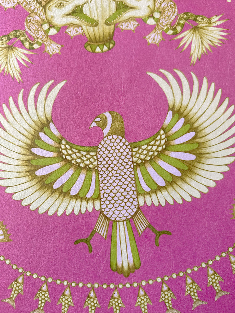 Intricate winged birds and fish motifs in gold lustre on bold fuchsia Nefertiti Pink wallpaper.