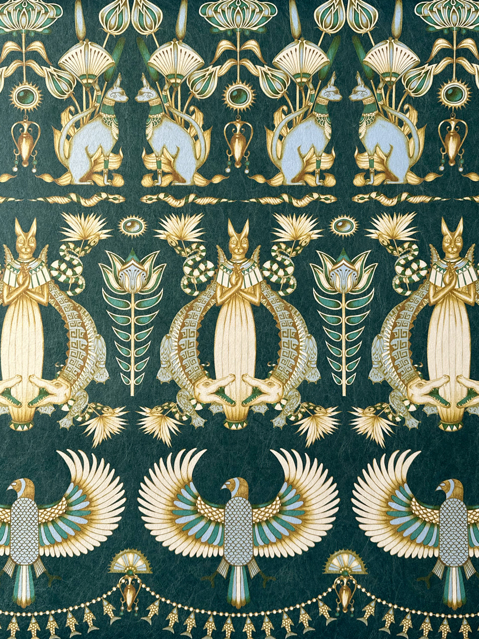 Close-up of Egyptian art deco motifs on luxury wallpaper in duck egg and gold hues.