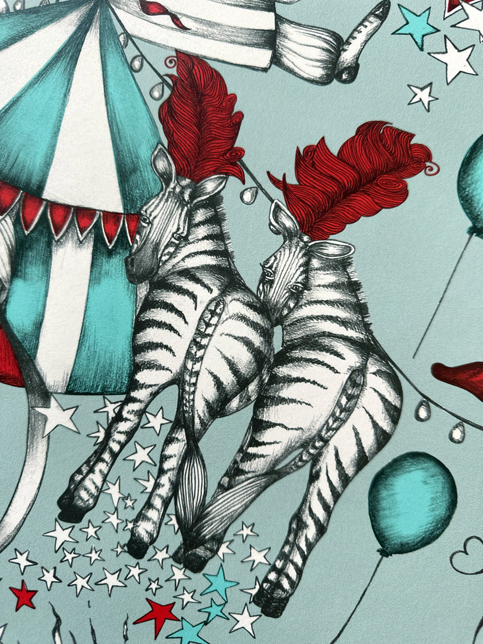 Illustration of two zebras with red feathers, circus tent, and balloons on a light blue background.