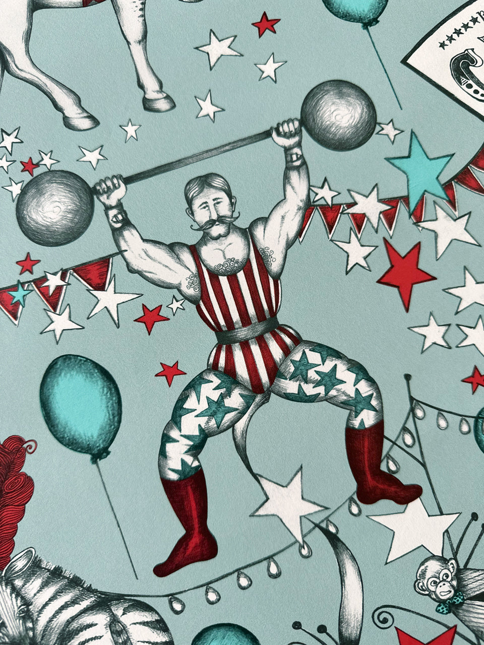 Vintage-style illustration of a strongman performer with circus elements on a duck egg blue background.